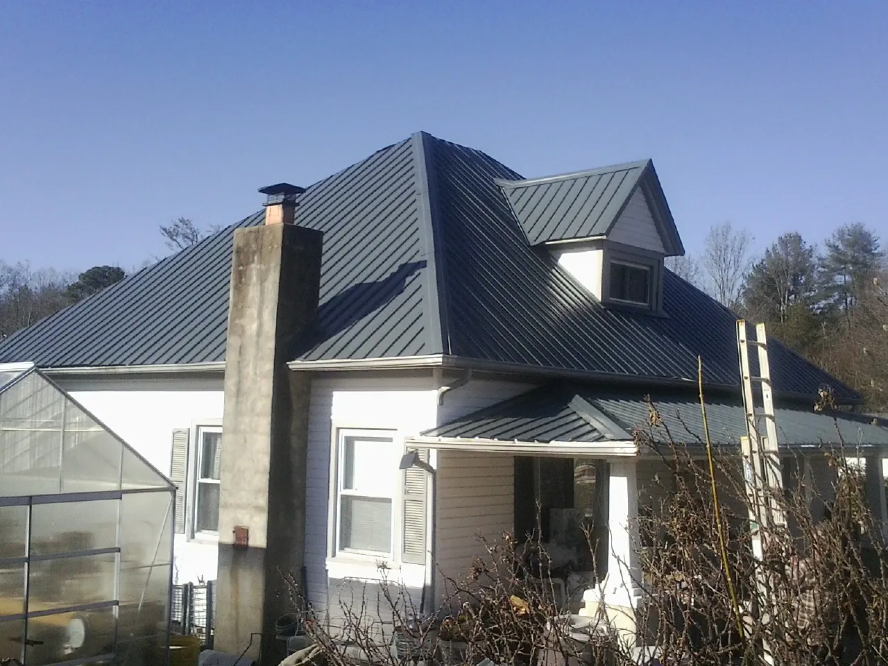 Dark blue standing seam metal roof on a white farmhouse with dormer — Slate & Tile Roof Repair by Roofing Brothers in Toquerville
