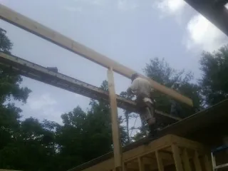 Carpenter setting a ridge beam over a new addition frame — Ice Dam Removal by Roofing Brothers in Toquerville