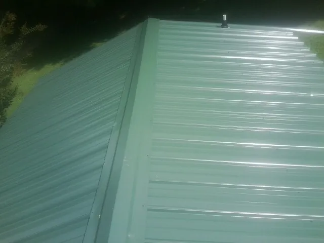 New green metal panels meeting at the ridge of a roof — Flat Roof Repair work by our crew in Toquerville