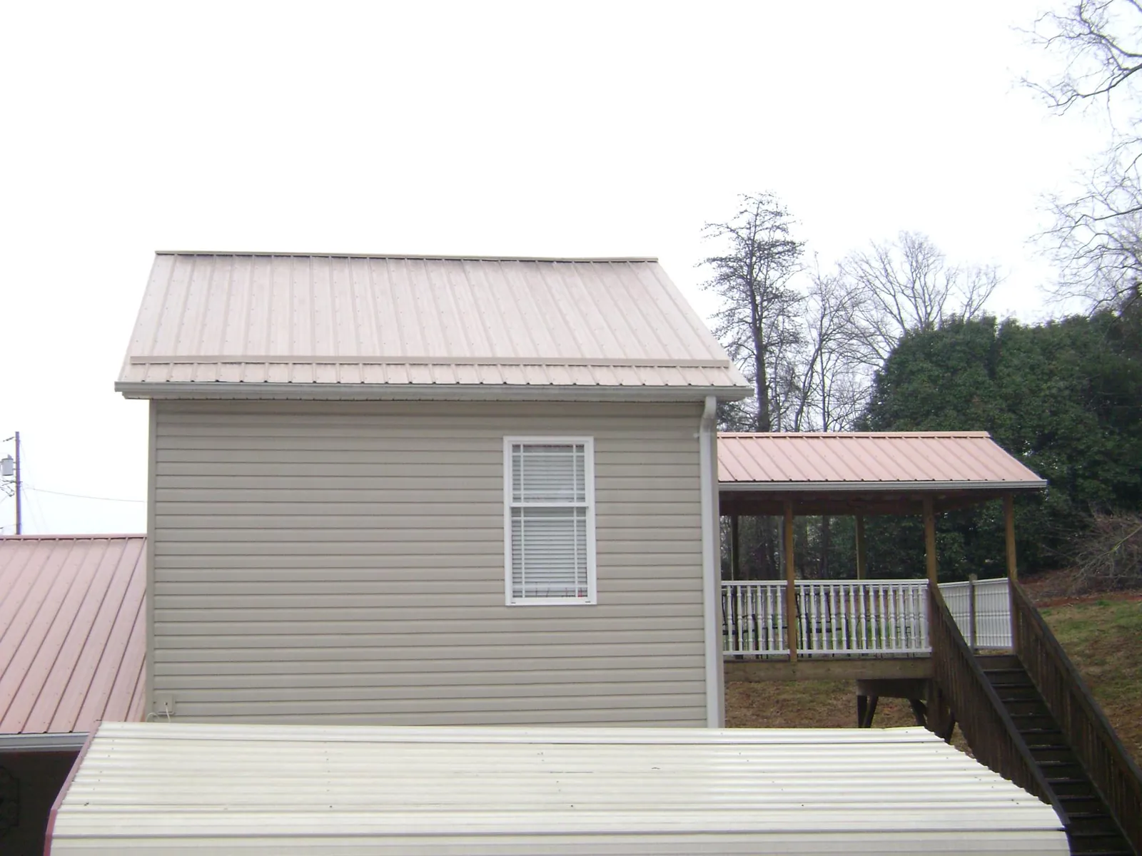 Tan metal roofs on a two story addition and attached porch, from a Roof Replacement job in Toquerville