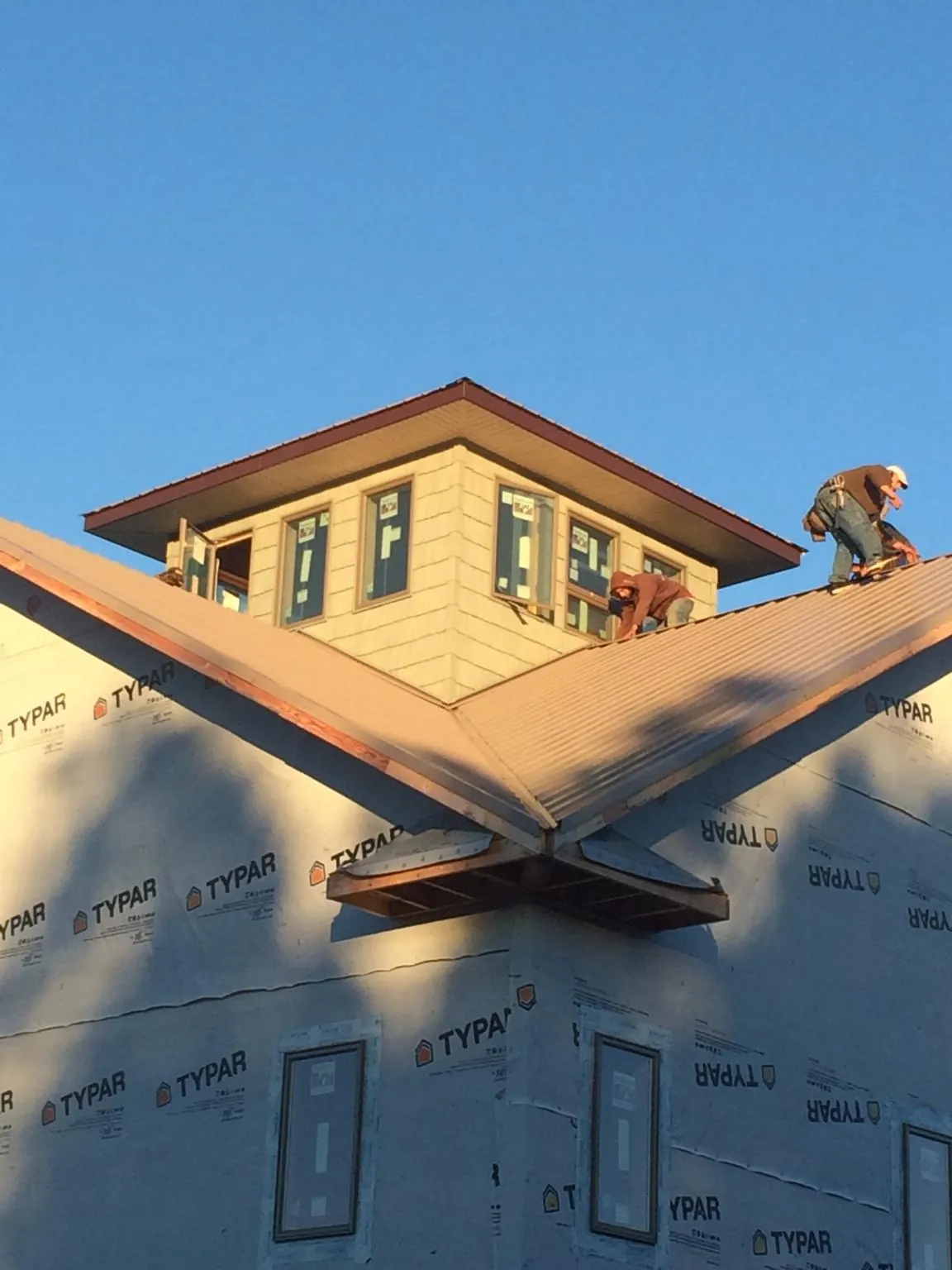Roofers working around a rooftop cupola on a new metal roof at sunset — Roof Waterproofing in Toquerville by Roofing Brothers